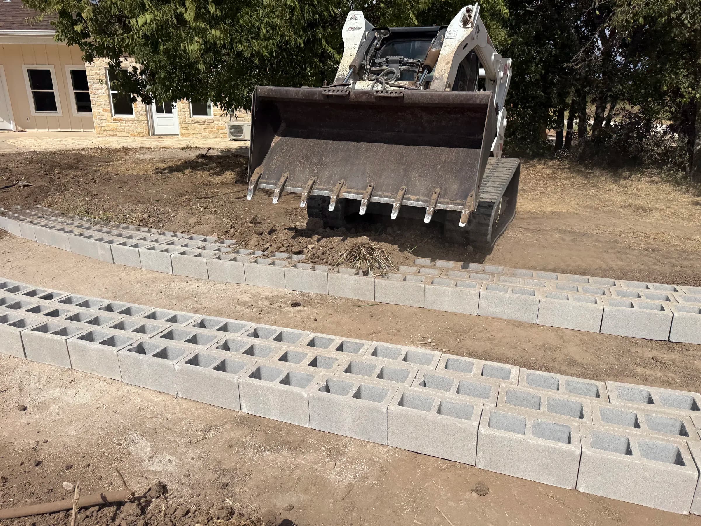Branded B skid steer working beside the open-cell concrete driveway at White Hall