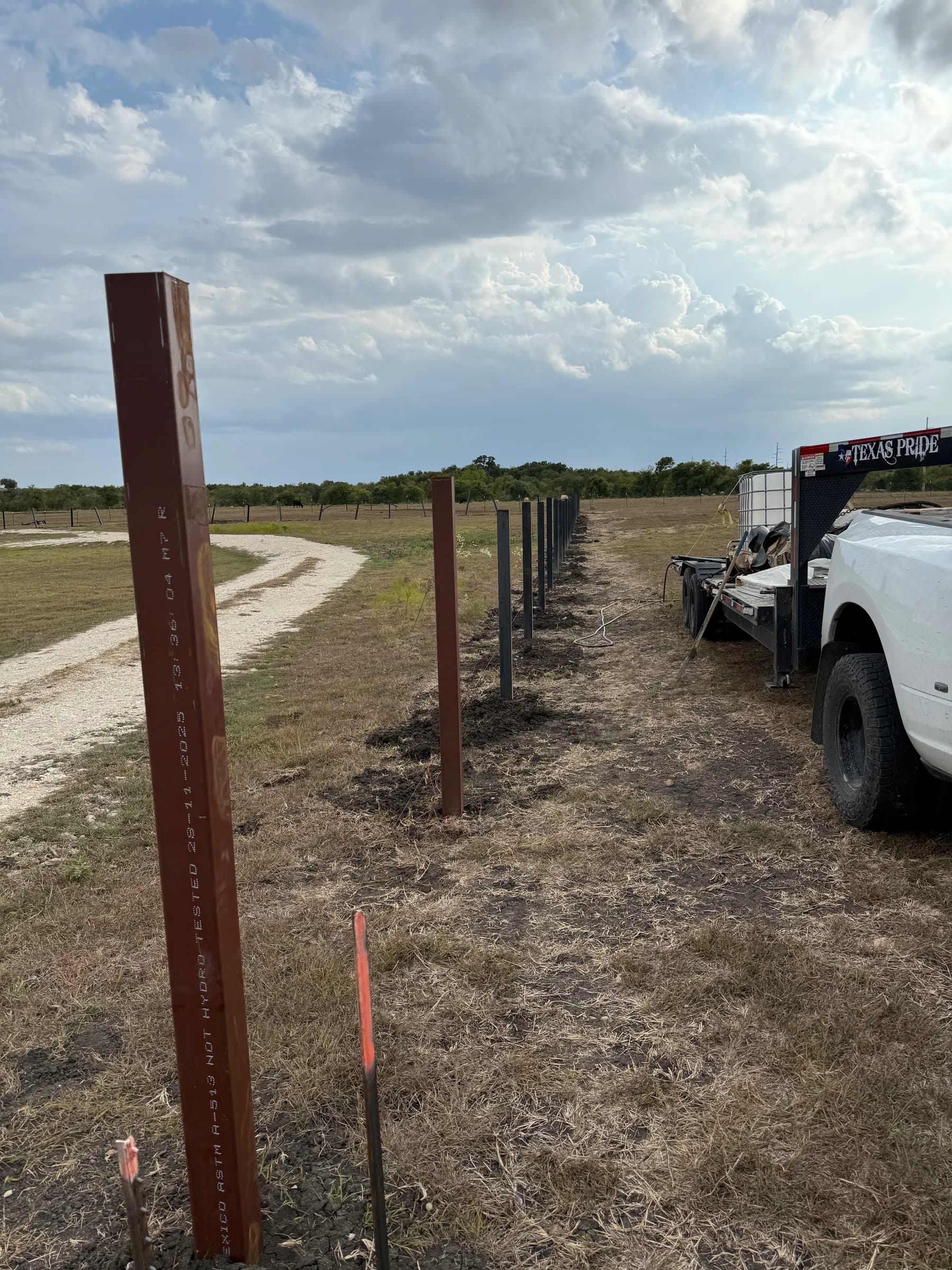 Steel fence posts beside the gravel drive at the Holland project